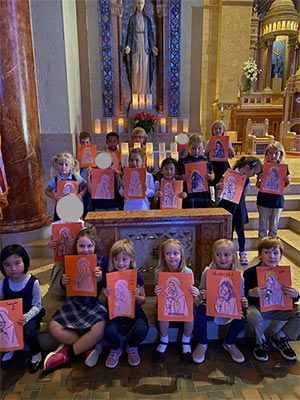 Students holding up their colored drawing of Mary