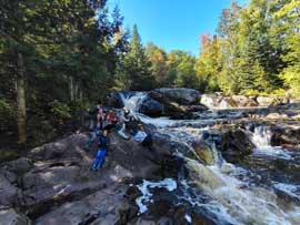 Students sitting on rocks beside river