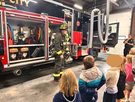 Students watching a fireman show equipment on the truck