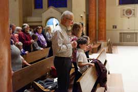 Students and grandparents standing at pews