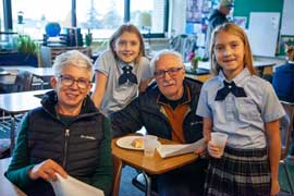 Grandparents sitting at desks next to two students