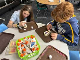 Students gluing glitter onto miniature coffins