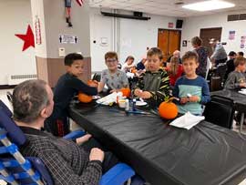 Adult watching students prepare to paint pumpkins