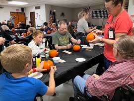 Students and adults paining pumpkins