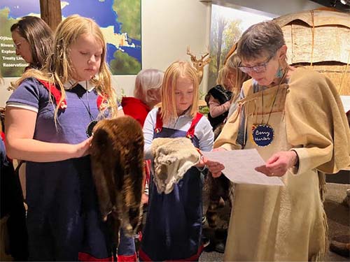 two students holding animal pelts