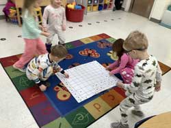 young students playing with posterboard on the floor