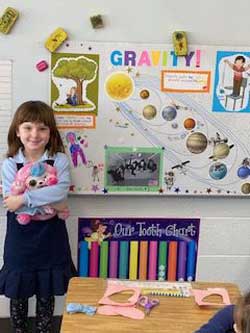 boy standing next to his poster about part of the solar system.