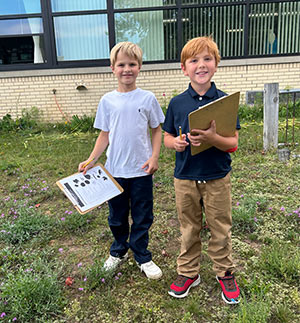 Two boys with their note pads for the scavenger hunt
