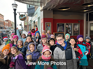 Third and fourth grade students standing in front of theater - View More Photos