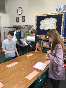 Students writing and reading papers in classroom
