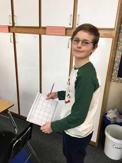 boy smiling while holding paper and pencil