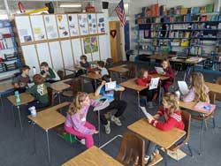 students sitting at desks in classroom with papers in their hands