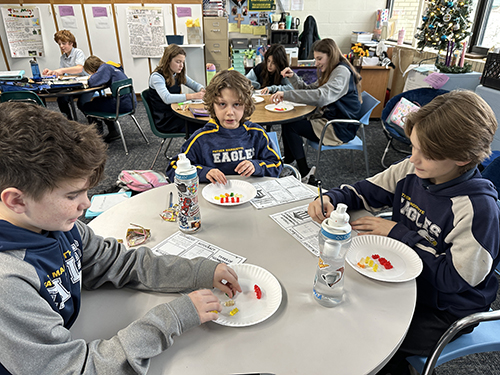 Sixth grade students at a table learning about forms of government using gummy bears