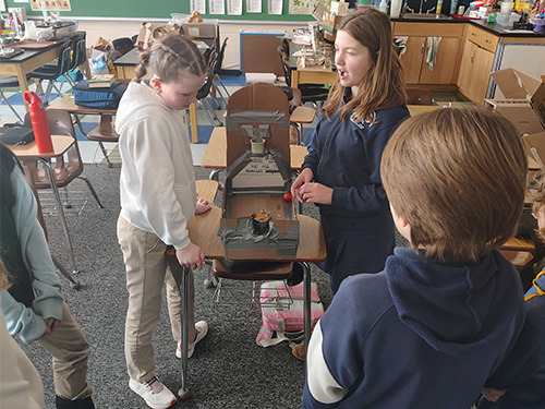 Students giving a presentation about a cardboard display with a basket
