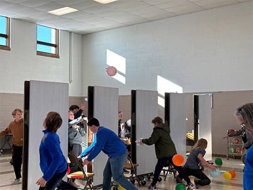 Students throwing balloons over tables