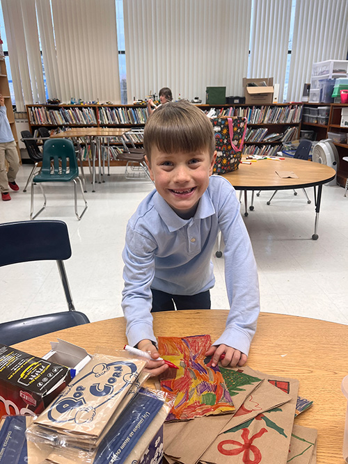 Young man at a table decorating a bag