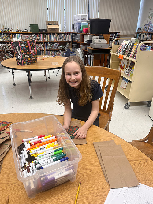 Young girl at a table decorating a bag
