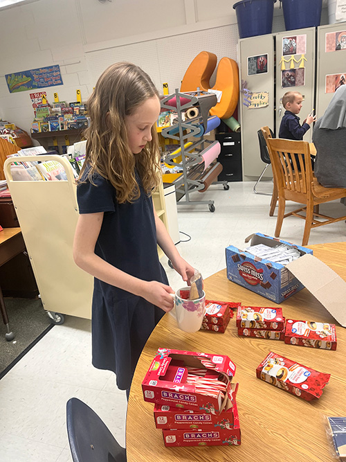 Young girl at a table filling coffee mug with small gifts