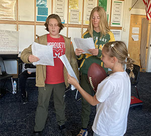 Three students acting out and reading a script