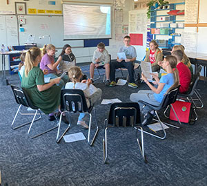 Students and teacher sitting in a circle reading the play