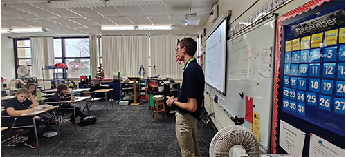 Seminarian visiting and talking with students in the classroom