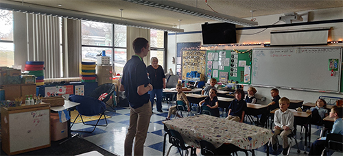 Students engaged in learning from a Seminarian visiting the school
