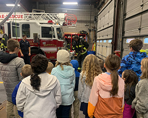 students watching firemen next to firetruck