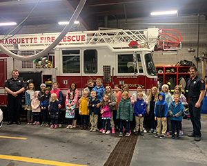 students lined up with firemen next tot eh firetruck