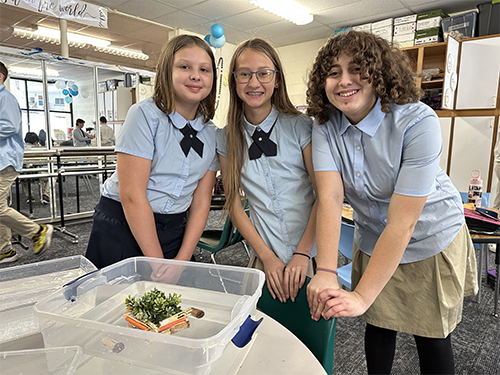 Three happy girls posing in front of their project