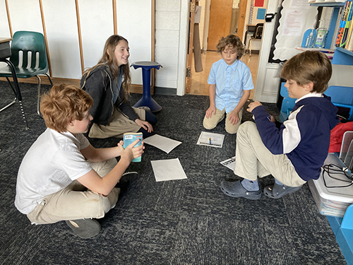 Middle school students sitting on the classroom floor talking with each other