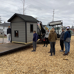 New playhouse being delivered on truck while MSHS students watch