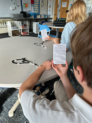 Two girls with their prayer cards at a table