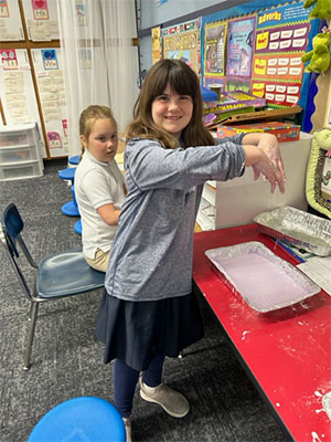 Student playing with her oobleck tray and standing up