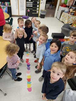students standing around colored ice cream scoop shaped papers on the ground