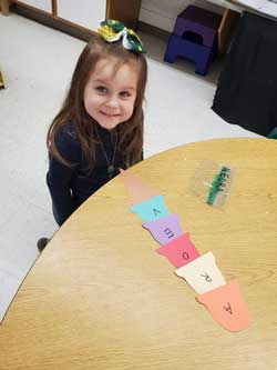girl smiling after making a paper ice cream cone with letter veora on it