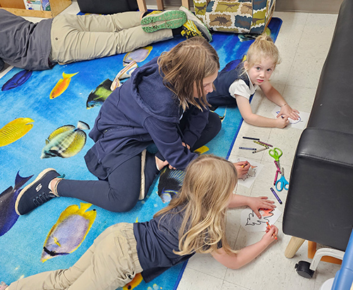 Group of girls coloring together on the classroom floor