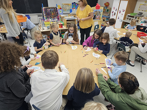 Pre-k and older students sitting together at a round table