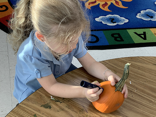 Close up of pre-kindergarten student decorating her pumpkin