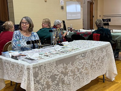 Lady sitting behind a display table with jewelry items