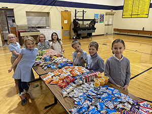 Happy K-4 students next to snacks on table in gym
