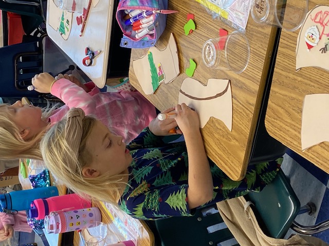 First grader coloring in a paper wooden shoe at her desk