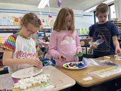 three students working with marshmallows, toothpicks and legos