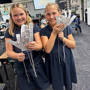 Two students holding up paper hands