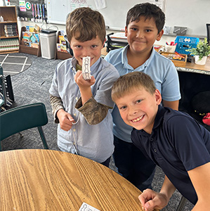 Three students, one is holding a paper finger