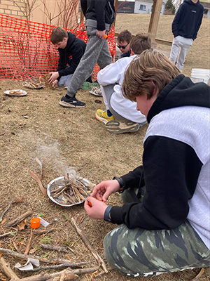 One male student making a fire