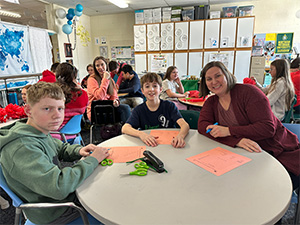 staff member and two male students at a table
