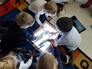 children looking at photo of hand